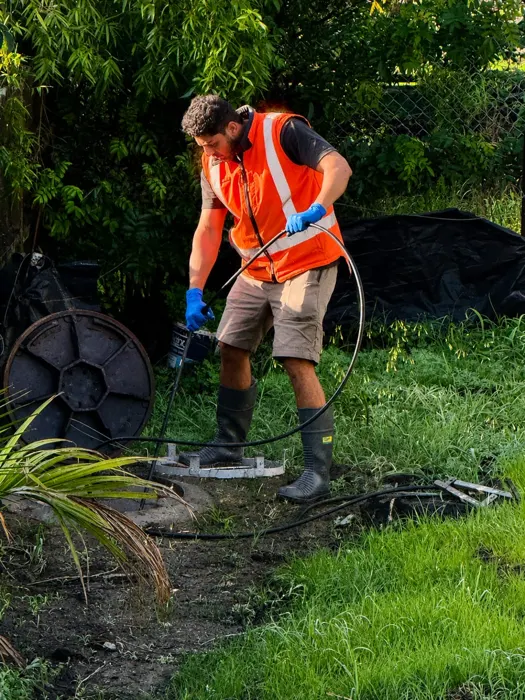 Speed Drain technician in a hi-vis vest working at a drain