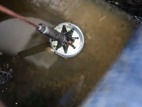 Drain camera lowered into a drain for a CCTV inspection